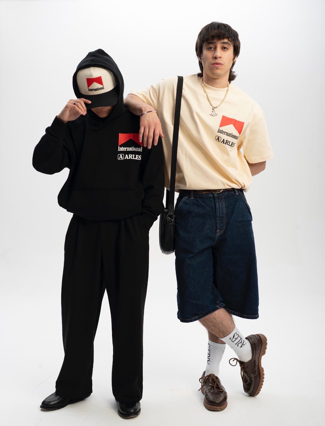 Two people wearing branded clothing with visible logos on a white background
